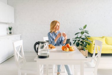 Mutlu kadın sütlü kahve içer, mutfakta kahvaltı. Sabah evde kadın kişi, sağlıklı beslenme ve yaşam tarzı