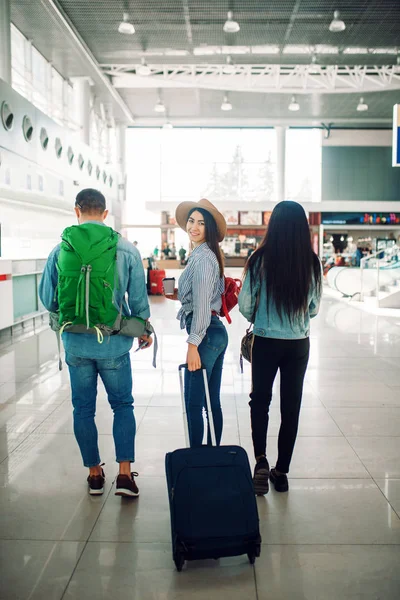 空港内の荷物を持つ3人の観光客 バックビュー エアターミナルで手荷物をお持ちのお客様 楽しい旅 夏の旅行 — ストック写真