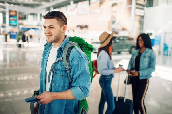 Male Tourist Backpack Holds Passport Airport Two Female Companions Background — Stock Photo, Image