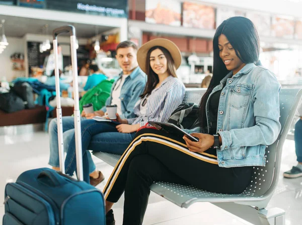 空港で出発を待っているスーツケースを持つ女性黒人観光客 航空ターミナルでのフライトを楽しみにしている手荷物を持つお客様 幸せな旅 — ストック写真