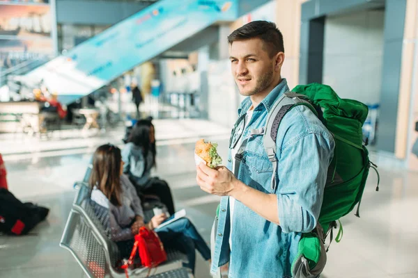 Male Tourist Backpack Holds Burger Female Travelers Waiting Departure Airport — Stock Photo, Image