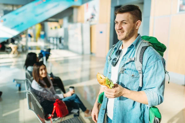 Male Tourist Backpack Holds Burger Female Travelers Waiting Departure Airport — Stock Photo, Image