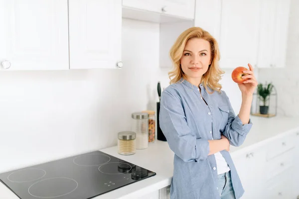 白雪姫のインテリアで台所でリンゴのポーズをとる女性の肖像画 朝の在宅女性 健康的な栄養とライフスタイル — ストック写真