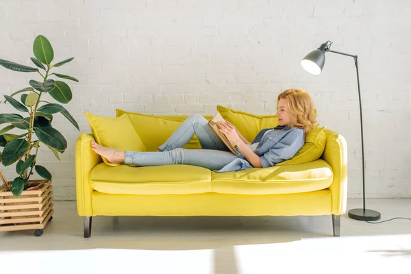 Mujer Joven Acostada Acogedor Sofá Amarillo Leyendo Libro Sala Estar —  Fotos de Stock