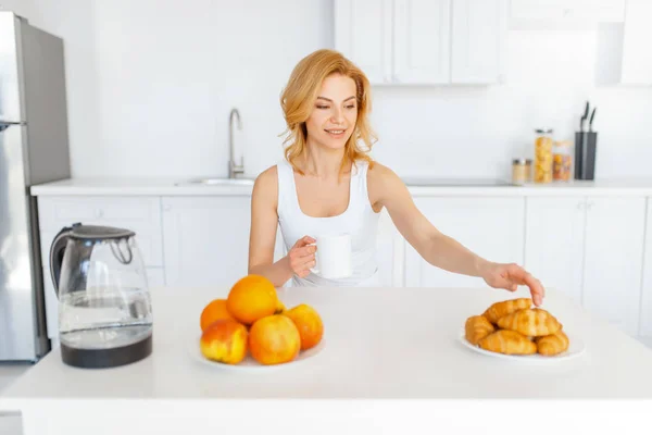 テーブルで幸せな女性 キッチンでフルーツの朝食 朝の家庭での女性人 健康的な栄養とライフスタイル — ストック写真