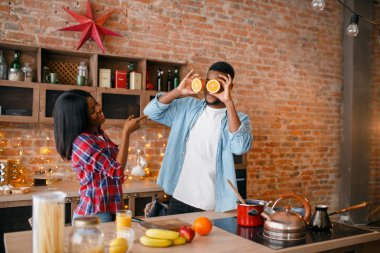 Neşeli siyah çift mutfakta yemek yaparken eğleniyor. Afrikalı aile evde sebze salatası hazırlıyor. Sağlıklı vejetaryen yaşam tarzı