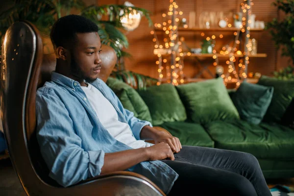 黑人坐在客厅舒适的皮椅上 在家放松 年轻的非洲裔美国男性在他的房子 — 图库照片
