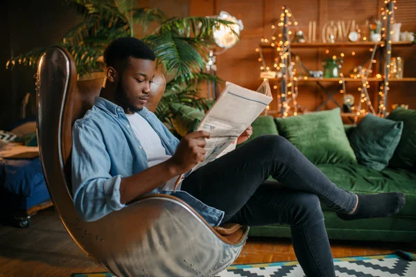 黑人在客厅舒适的皮椅上看报纸 在家放松 年轻的非洲裔美国男性在他的房子 — 图库照片