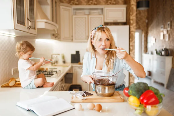 若い母親と娘は溶かしたチョコレートを味わう キッチンでかわいい女性と女の子の料理 ペストリーの準備 幸せな家族はカウンターで甘いデザートを準備します — ストック写真