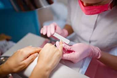 Kozmetoloji salonu, manikür, tırnak parlatma prosedürü. Güzellik mağazasında kadın müşteri için el bakımı tedavisi, kozmetolojist kadın, tırnakile usta çalışır