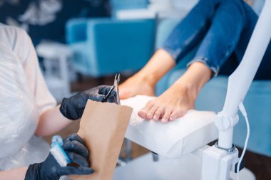 Kozmetolog salonu, pedikür, kırpma prosedürü. Güzellik dükkanında kadın müşteri için tırnak bakım tedavisi, eldiven Doktor müşteri ayak tırnaklarını ile çalışır