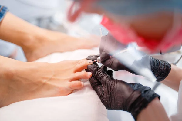 美容师沙龙 抛光程序 美容店的女客户指甲护理治疗 戴手套的医生与客户的脚趾甲合作 — 图库照片