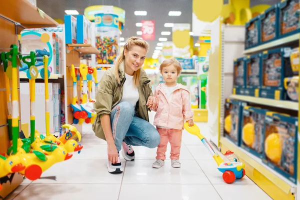 子供の店で小さな娘を持つ母 スーパーでおもちゃを選ぶママと子供 家族の買い物 — ストック写真