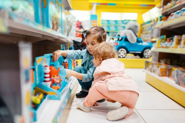 キッズストアの棚に小さな男の子と女の子 側面のビュー スーパー 家族の買い物 若い顧客でおもちゃを選ぶ兄弟姉妹 — ストック写真