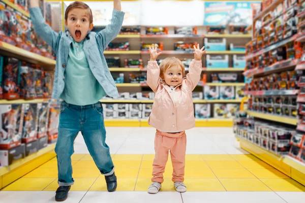 小男孩和小女孩举手在儿童商店的货架上 快乐的孩子们 兄妹在超市选择玩具 家庭购物 年轻顾客 — 图库照片