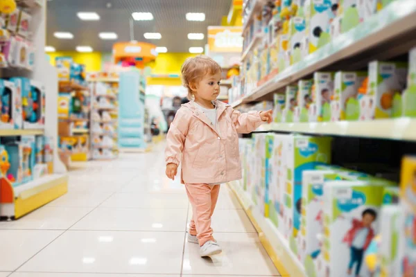 Маленькая Девочка Полке Выбирает Игрушки Детском Магазине Вид Сбоку Дочь — стоковое фото