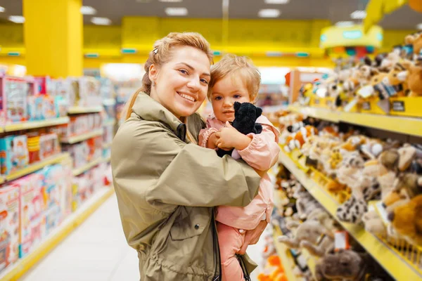 子供の店でぬいぐるみ犬を選択する彼女の小さな女の子と母 一緒にスーパーマーケットでおもちゃを買うママと子供 家族の買い物 — ストック写真