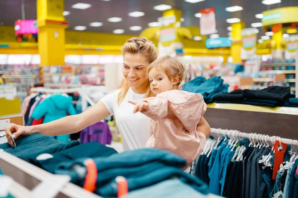 子供の店で服を選ぶ彼女の小さな娘と母 一緒にスーパーマーケットでドレスを買うママと子供 家族の買い物 — ストック写真