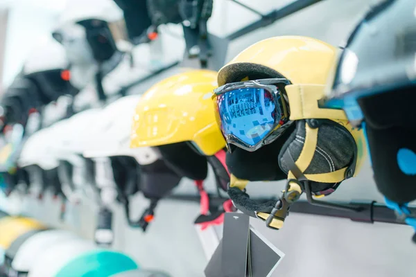 スポーツショップ クローズアップ 誰もマスクとスキーやスノーボードのヘルメットの列 冬のアクティブレジャー 保護機器付きショーケース — ストック写真