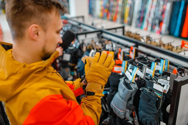 Man trying on gloves for ski or snowboarding, sports shop. Winter season extreme lifestyle, active leisure store, male customer with protect equipment