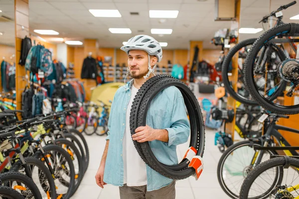 자전거 헬멧을 남자는 자전거 타이어를 스포츠 숍에서 극단적 라이프 스타일 — 스톡 사진