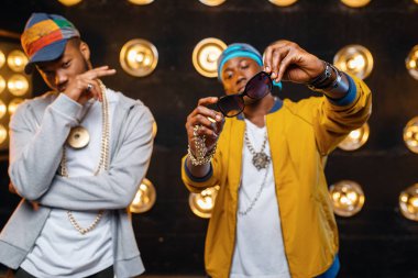 Kapaklı iki siyah rapçi, arka planda spot ışıkları olan sahnede şarkıcılar. Işıklar, yeraltı müzik konseri, kentsel tarzı ile sahnede Rap sanatçıları