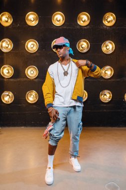 Kap siyah rapçi, arka planda spot ışıkları ile sahnede perfomance. Işıklar, yeraltı müziği, kentsel tarzı ile sahnede Rap sanatçısı