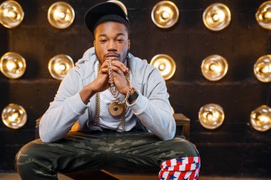 Kap pozlar Afrikalı rapçi, arka planda spot ışıkları ile sahnede perfomance. Işıklar, yeraltı müziği ile sahnede Rap sanatçısı