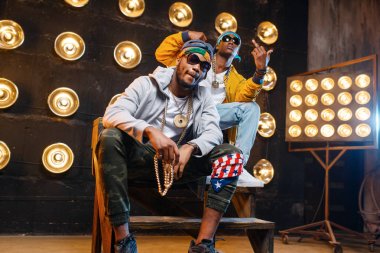 İki Afrikalı rapçi merdivenlerde oturuyor, sahnede arka planda spot ışıkları yla perfomance. Işıklar, yeraltı müziği, kentsel tarzı ile sahnede Rap sanatçıları