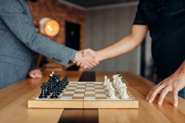 Erkek satranç oyuncuları maçtan önce el sıkışırlar. İki satranç oyuncusu entelektüel turnuvaya kapalı mekanlarda başlar. Ahşap masa üzerinde satranç tahtası