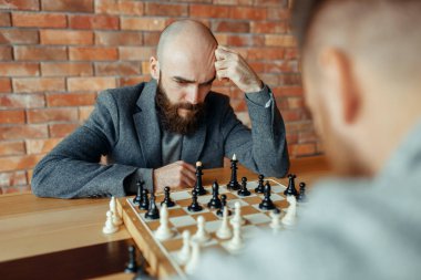 Erkek satranç oyuncuları, düşünme süreci oynuyor. İki satranç oyuncusu, entelektüel turnuvaya kapalı olarak başlar. Ahşap masa üzerinde chessboard, strateji oyunu