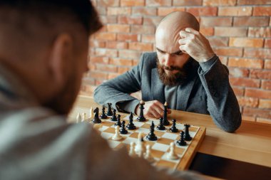 Erkek satranç oyuncuları, düşünme süreci oynuyor. İki satranç oyuncusu, entelektüel turnuvaya kapalı olarak başlar. Ahşap masa üzerinde chessboard, strateji oyunu