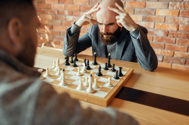 Erkek satranç oyuncuları, düşünme süreci oynuyor. İki satranç oyuncusu, entelektüel turnuvaya kapalı olarak başlar. Ahşap masa üzerinde chessboard, strateji oyunu
