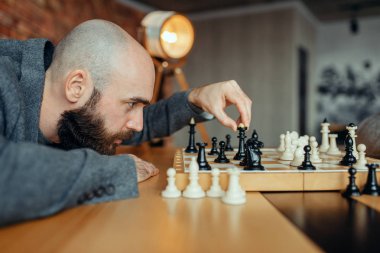 Erkek satranç oyuncusu siyah rakamlar oynuyor, Kraliçe hareket. Gemide chessplayer, entelektüel turnuva kapalı. Ahşap masa üzerinde chessboard, strateji oyunu