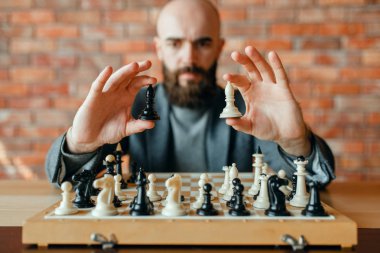 Erkek satranç oyuncusu beyaz ve siyah figürler, ön görünüm tutar. Gemide chessplayer, entelektüel turnuva kapalı. Ahşap masa üzerinde chessboard, strateji oyunu