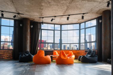 Panoramik şehir manzarasına sahip daire stüdyosu, kimse. Büyük pencereler, sehpa ve modern sandalyeler ile grunge tarzı oturma odası, arka planda gökdelenler ile şehir merkezinde, panorama