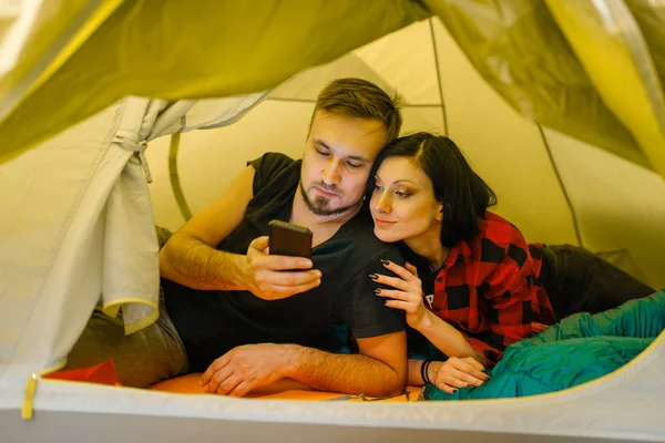 観光テントに横たわっている電話を持つカップル スポーツショップの顧客 アクティブレジャー プロの旅行機器 — ストック写真