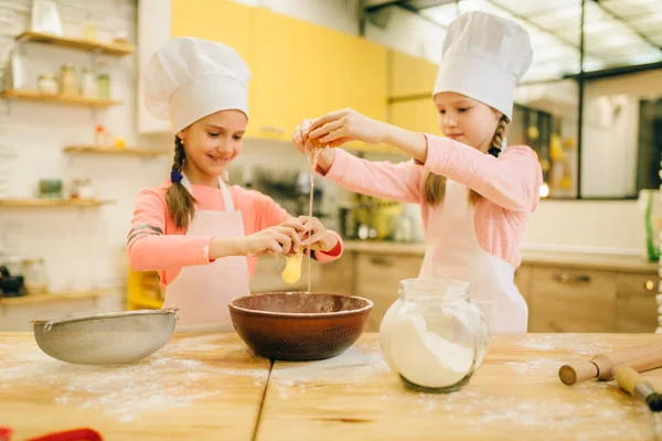 Duas Irmãs Pequenas Cozinheiras Bonés Amassam Ovos Uma Tigela Preparação — Fotografia de Stock