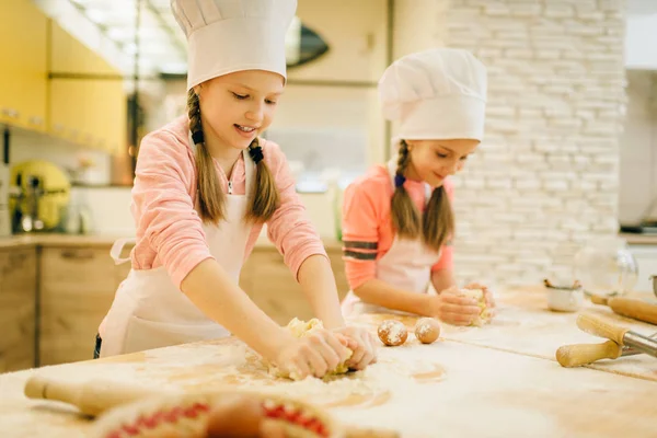 2人の小さな女の子のシェフは キッチン上のクッキーの準備 面白いパン屋をくしゃくしゃにします 子供たちはペストリーを調理し 子供たちはケーキを準備する料理を作ります — ストック写真