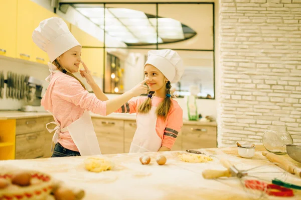 Duas Meninas Sorridentes Cozinheiras Bonés Aventais Divertindo Preparação Biscoitos Cozinha — Fotografia de Stock