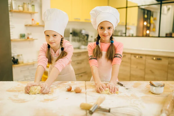 Duas Meninas Sorridentes Cozinheiras Bonés Aventais Divertindo Preparação Biscoitos Cozinha — Fotografia de Stock