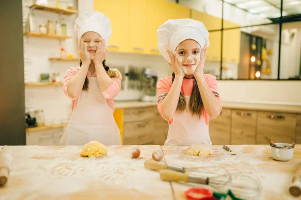 二人の小さな女の子のシェフは キッチンで小麦粉 クッキーの準備で自分の顔を塗ります 子供たちはペストリーを調理し 楽しみを持って 子供たちはケーキを準備します — ストック写真