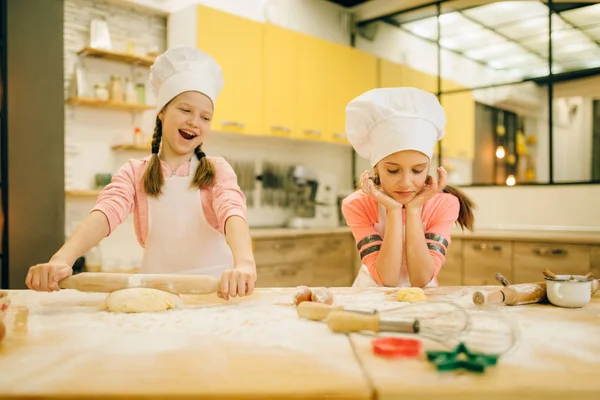 2人の小さな女の子のシェフがお互いに笑っている キッチンでクッキーの準備 子供たちはペストリーを調理し 楽しみを持って 子供たちはケーキを準備します — ストック写真
