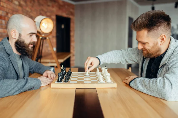 男棋手开始下棋 第一个动作 两位棋手在室内开始智力比赛 木桌上的棋盘 战略游戏 — 图库照片