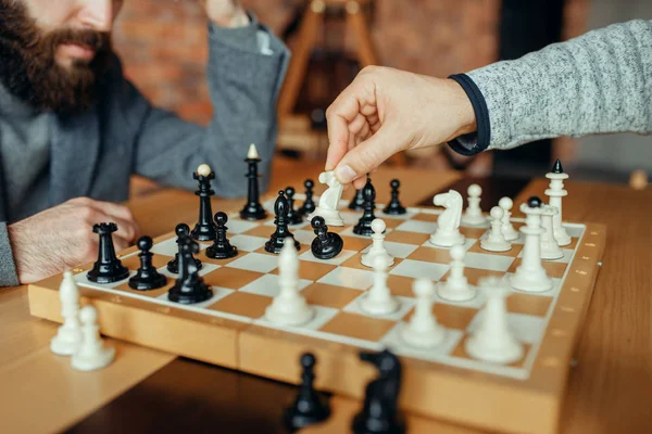 ボードで遊ぶ男性チェスプレイヤー 白騎士はポーンを取ります 2人のチェスプレイヤーが屋内で知的トーナメントを開始します 木製テーブルのチェスボード — ストック写真