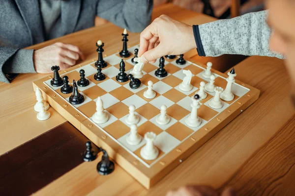 ボードで遊ぶ男性チェスプレイヤー 白騎士はポーンを取ります 2人のチェスプレイヤーが屋内で知的トーナメントを開始します 木製テーブルのチェスボード — ストック写真