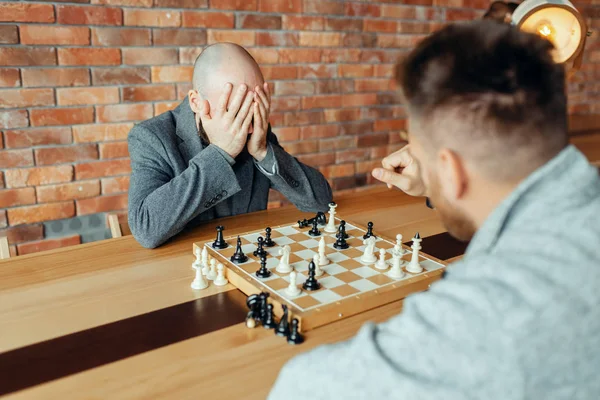 Os jogadores de xadrez masculinos começam a jogar, o primeiro movimento.  dois jogadores de xadrez começam o torneio intelectual dentro de casa.  tabuleiro de xadrez na mesa de madeira, jogo de estratégia