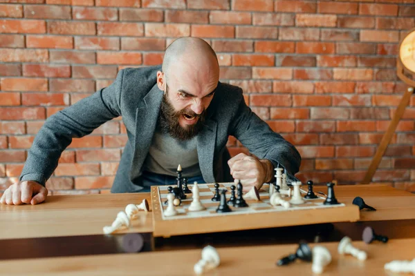怒っているチェスプレーヤーは 作品でボード上の彼の拳を打ちます 怒りのフィット感でチェスプレーヤーを強調 屋内の知的なトーナメント 木製テーブル 戦略ゲーム上のチェスボード — ストック写真