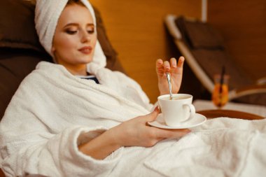 Spa sandalyede kahve fincan ı ile rahatlatıcı kafasına bornoz ve havlu seksi kız. Rahatlama eğlence, sağlıklı yaşam tarzı, çekici kadın koltukta dinlenme, güzellik salonu