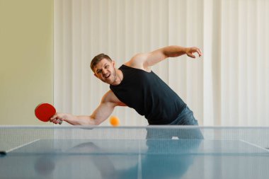Ping pong raket li adam topu kapalı oynar, eylem görüntü, kapalı egzersiz. Spor giyimerkek, masa tenisi kulübünde eğitim